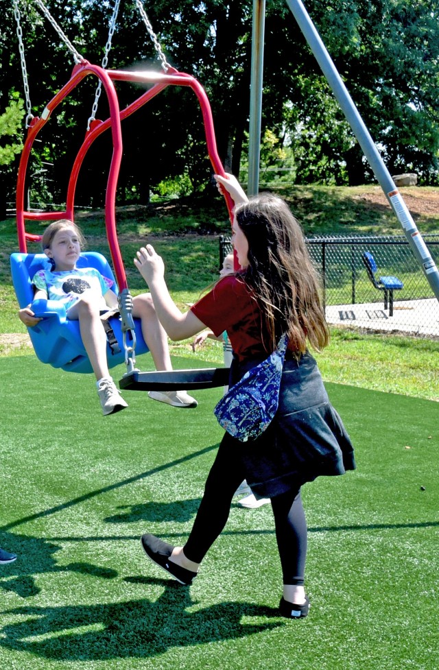 Madison Maxwell, 10, daughter of 1st Sgt. John Maxwell, 502nd Engineer Battalion, and Molly Griggs, 10, daughter of Maj. Charles Griggs, 1st Army Division, demonstrate how to use a swing designed for special needs and mobility impaired children at...