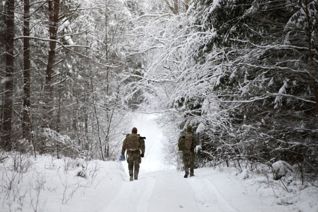 A U.S. Army Soldier with 2nd Battalion, 69th Armored Regiment “Panther Battalion,” 2nd Armored Brigade Combat Team, 3rd Infantry Division, walks beside a Romanian Soldier down a snowy path during the land navigation portion of the Croatian...