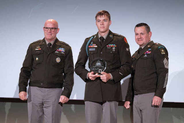 Spc. Mason Breunig of U.S. Army Pacific, center, accepts the Soldier of the Year award from Sgt. Maj. of the Army Michael R. Weimer at the Association of the U.S. Army Annual Exposition and Meeting on Oct. 14, 2024.