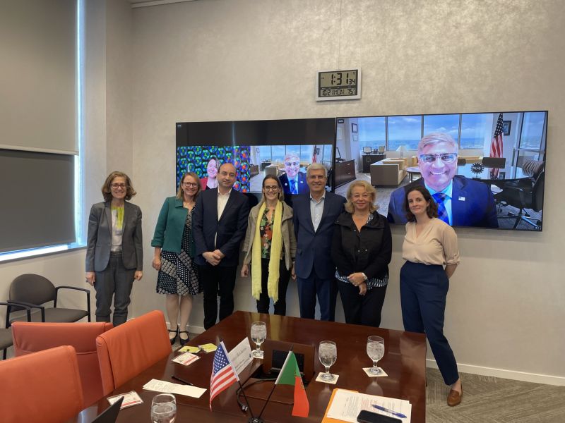 group of people standing in front of televisions hung on the wall for a virtual meeting