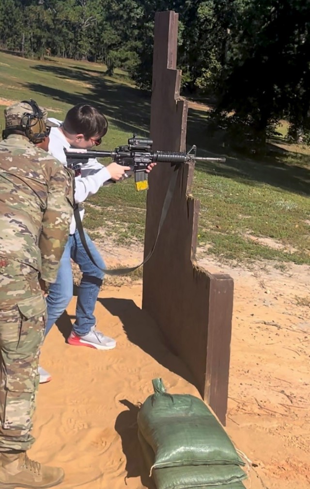 A drill sergeant shows Colin Messenger, 12, son of Lt. Col. Tony Messenger, 3rd Squadron commander, Second Security Force Assistance Brigade, Fort Liberty, North Carolina, how to shoot an M-4 carbine rifle during a battalion family day event at...