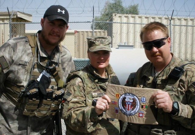 Master Sgt. Melissa O'Brien displays a mobile training team miniature guidon while supporting Operation Iraqi Freedom in 2011. She provided critical intelligence for Soldiers on the battlefield.