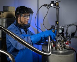 Wei Pan, performing a liquid helium transfer, turned a fascination with the smallest forms of matter into a career redefining how they are studied.(Photo by Randy Wong.) Click on the thumbnail for a high-resolution image.